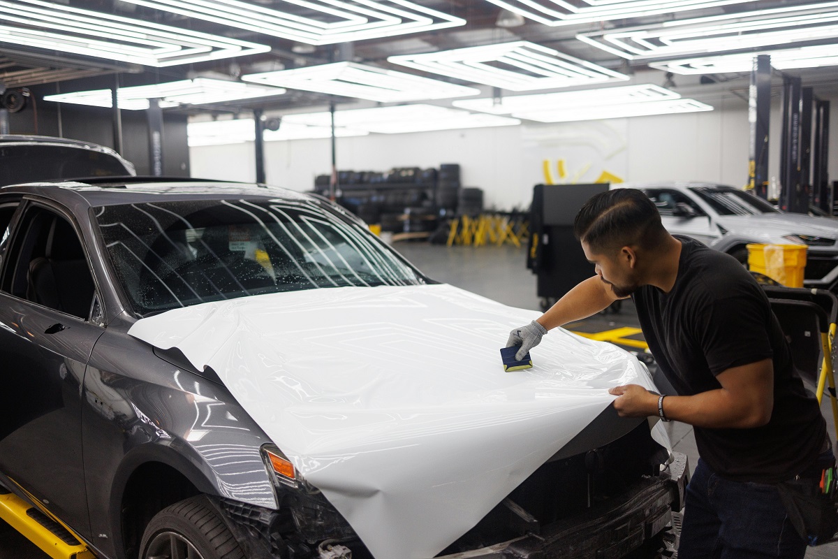 auto mechanic wrapping a car hood