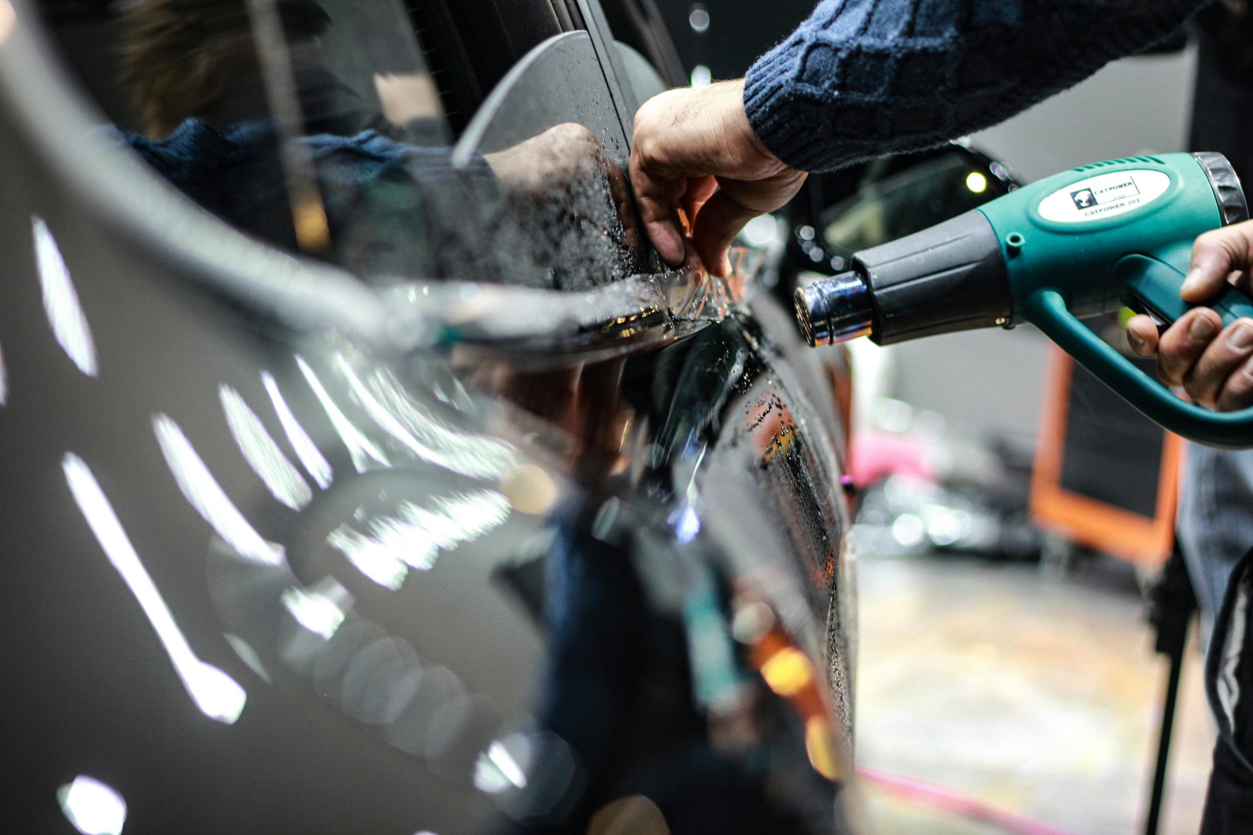 car owner using a heat gun on the door of a black car
