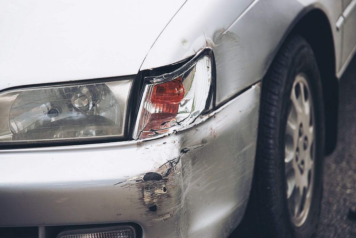 dent and broken headlight on a silver car
